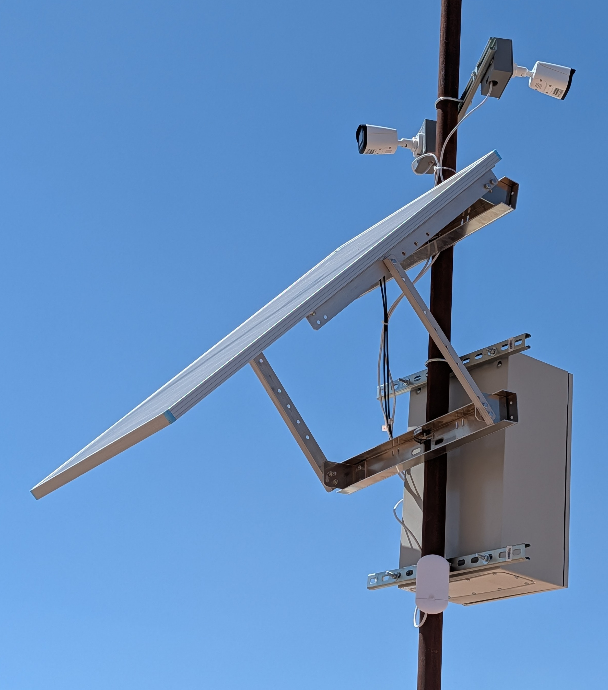 Solar panel, dual security cameras, and a wireless point-to-point radio mounted on a pole for an off-grid install